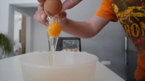 male hands cracking open a brown egg into a bowl on the kitchen counter slow motion