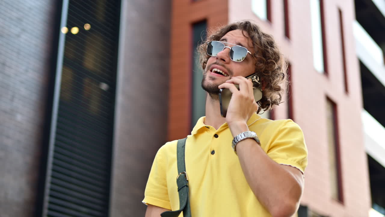 Man in yellow shirt talking on the phone while walking on the street