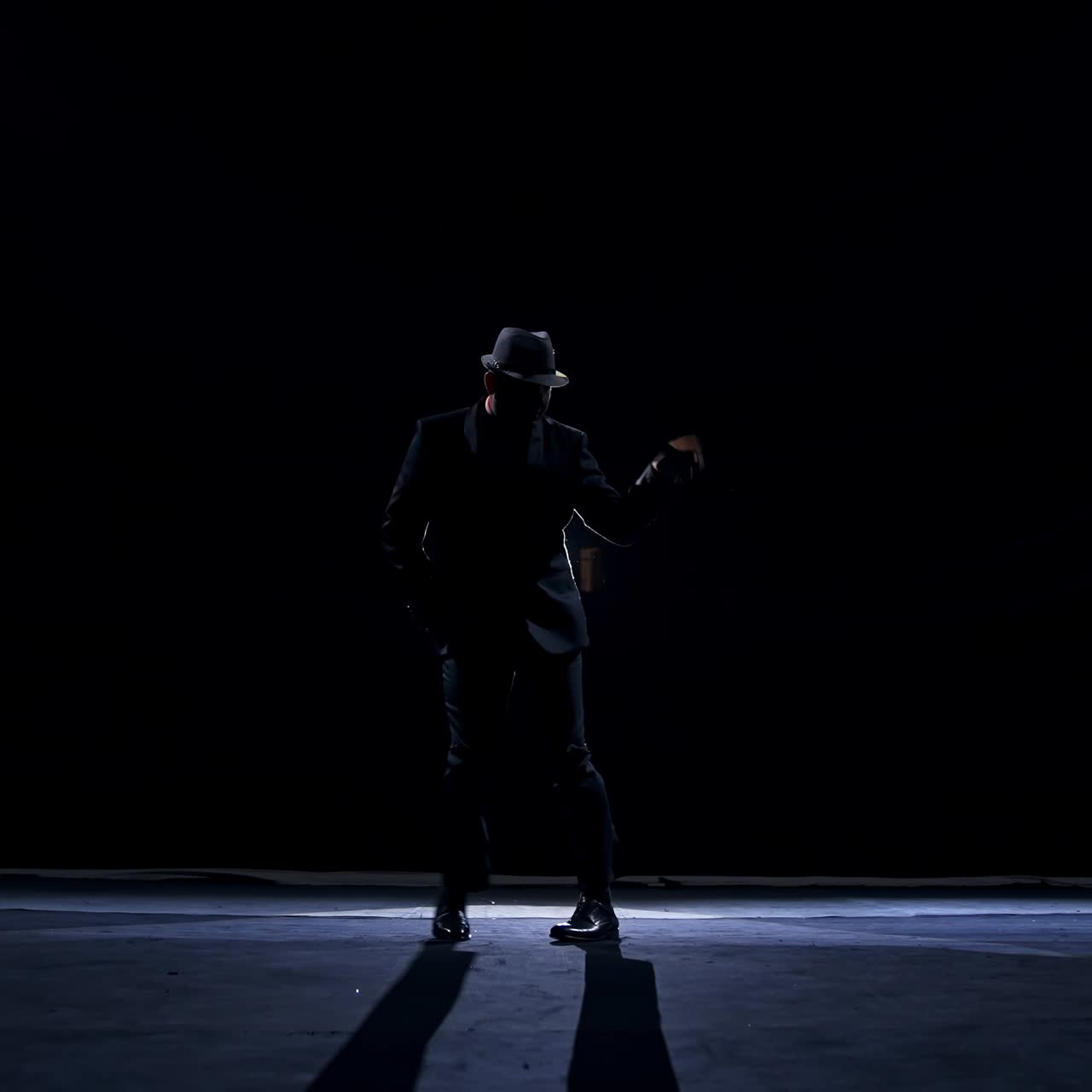 Uomo anziano in costume sul palco nell'oscurità. Uomo attivo con il cappello che balla sul palco durante lo spettacolo a teatro.