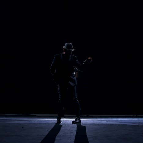 senior man in costume on stage in darkness. active man in hat dancing on stage during the performance in the theater