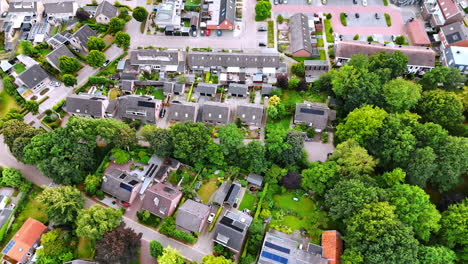 Footage above the grey roofs of the houses and lush greenery growing among them. Vierlingsbeek, Netherlands from top view