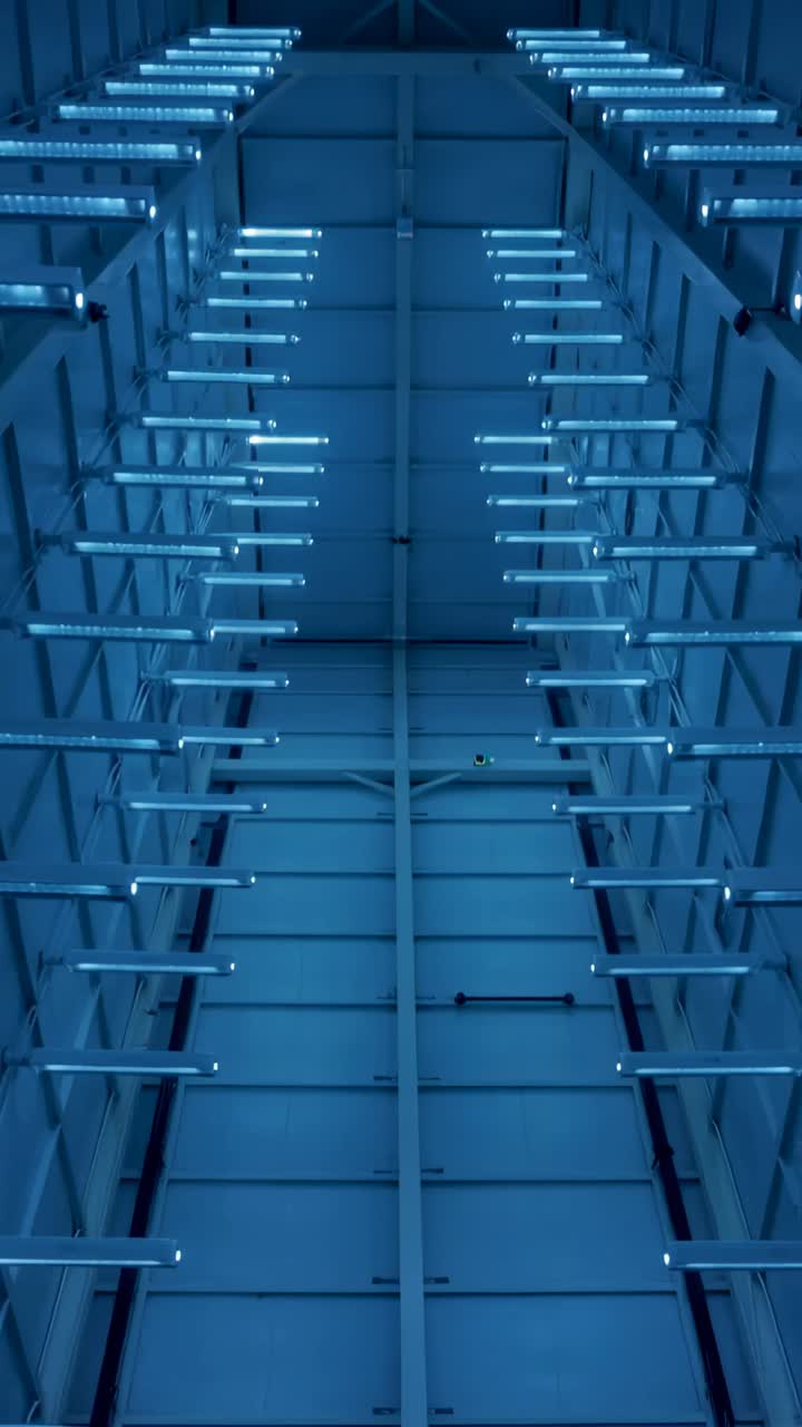 Vertical video: Powering tubular lights slowly lighting warehouse to reveal truss and brackets