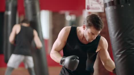 Man-boxer-punching-combat-bag-in-boxing-club.-Closeup-sportsman-training-kick.