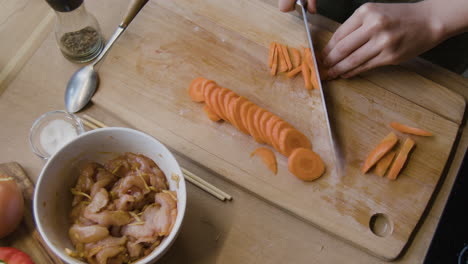 cooking stir fry: chopping carrots and preparing chicken