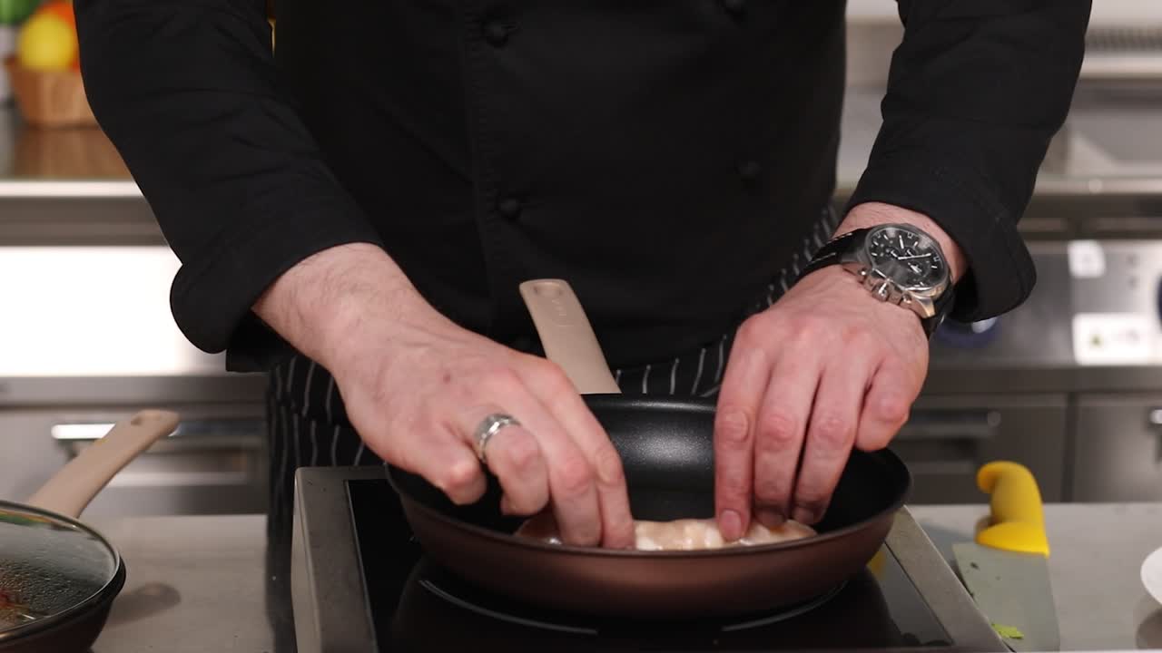 요리사 가 팬 에 소시지 를 조리 하고 있다