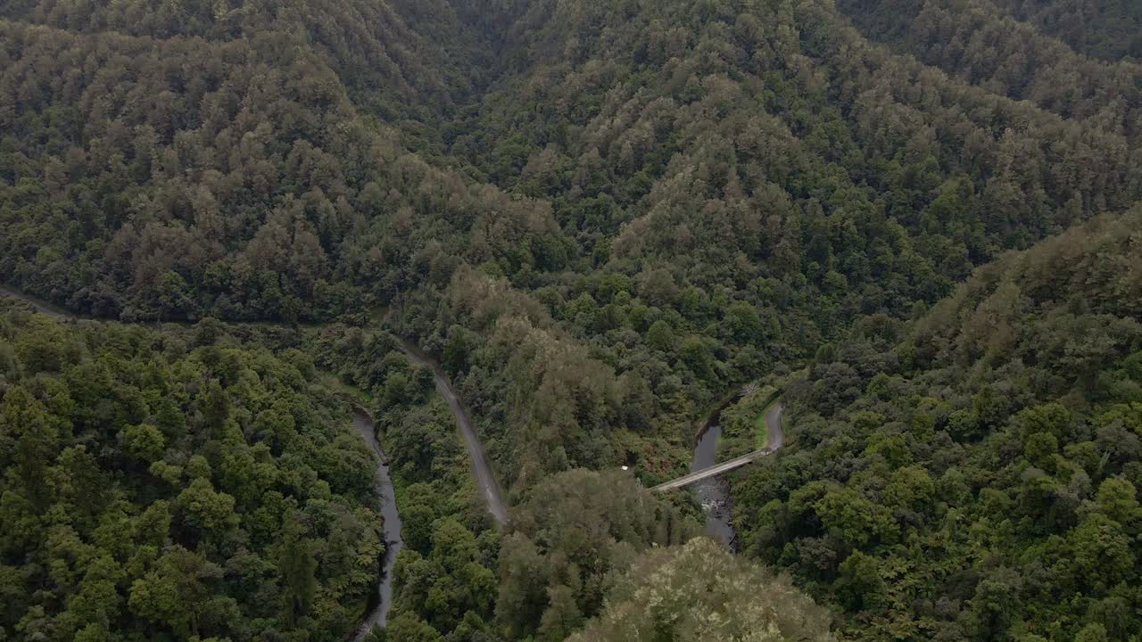 drone dando vueltas sobre un puente fluvial en la jungla de nueva zelanda