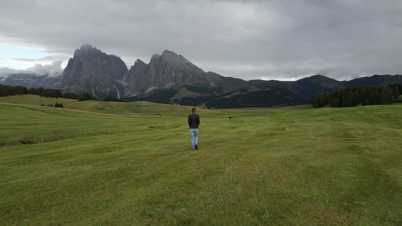 Woman walking in the Alpe di Siusi with Sassolungo in the background