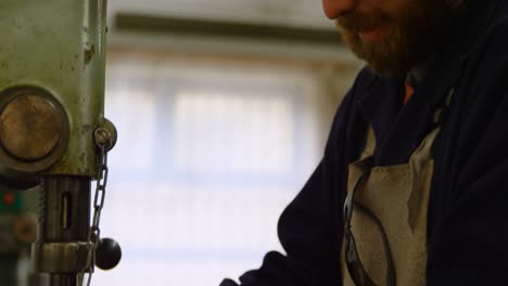 metalsmith using drill press machine in workshop 4k
