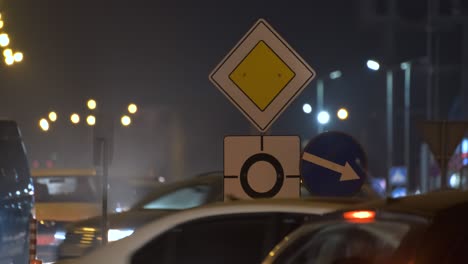 roundabout road signs with blurred cars on city street traffic at night. urban transportation concept