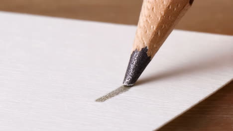 close-up of a pencil drawing a line on textured paper