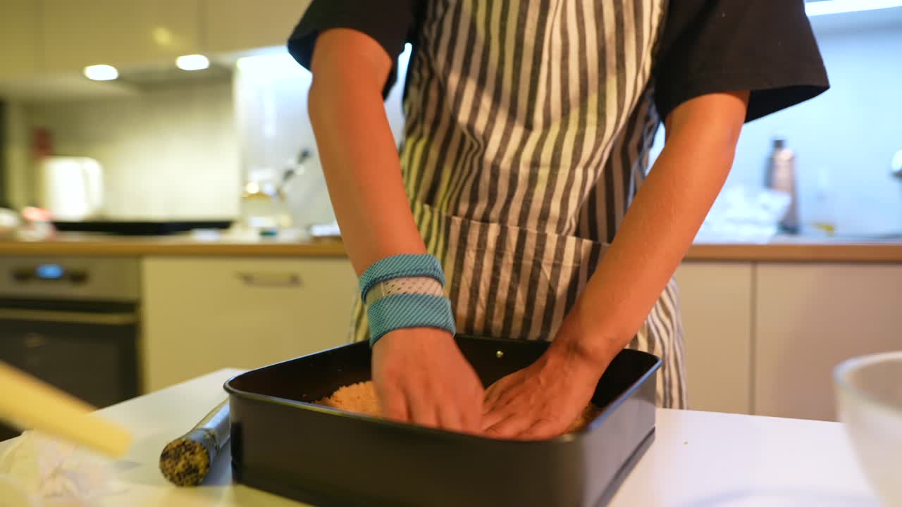 Manos de chef preparando masa en molde para hornear en una cocina moderna