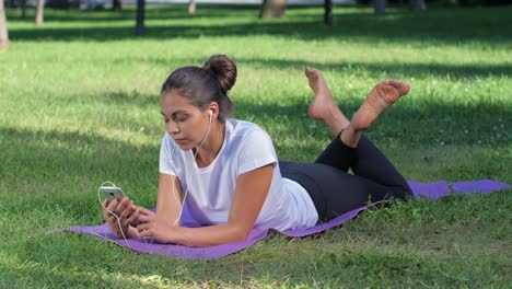 mujer relajándose en un parque en una alfombra de yoga