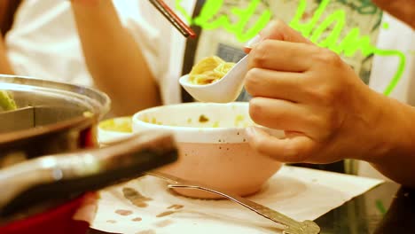 hands serving hotpot soup with chopsticks