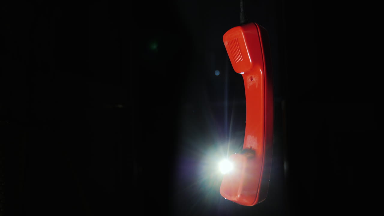 receptor de teléfono rojo de un teléfono retro colgado de un cable en un video de 4k de fondo negro