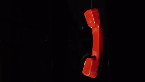 Red-Telephone-Receiver-From-A-Retro-Teléfono-Hanging-On-A-Wire-On-A-Black-Background-4K-Video