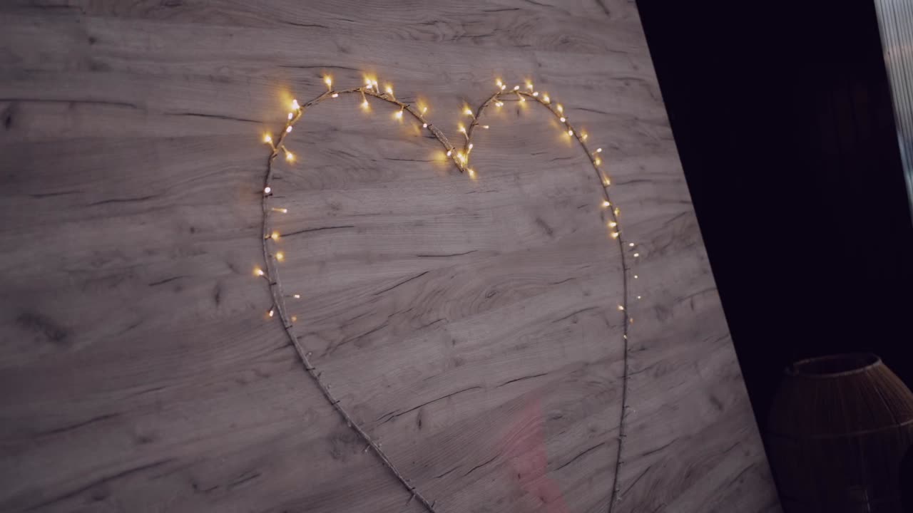 Pared de madera con un corazón luminoso formado por guirnaldas de luces retro