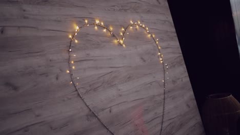 wooden wall with a glowing heart formed by retro string lights