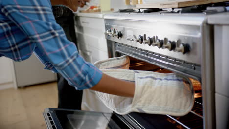 Happy-diverse-group-of-teenage-friends-cooking-and-baking-pizza-in-kitchen,-slow-motion