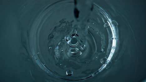 pure water filling glass top view closeup. crystal clear liquid stream bubbling