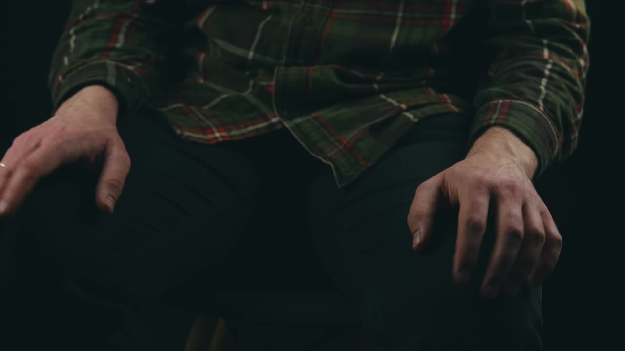 Close up footage of man having nervous tics with hands over dark background