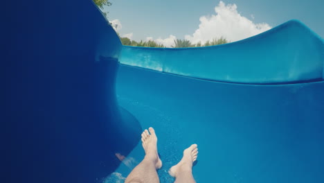 a man descends from a water slide looking only feet