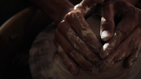 close-up of the hands of a male potter kneading wet clay on a potter's wheel