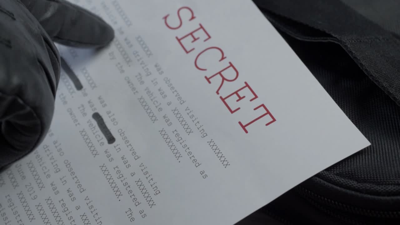 기밀 정보가 포함된 일급 비밀 문서를 읽는 검은색 장갑 낀 손