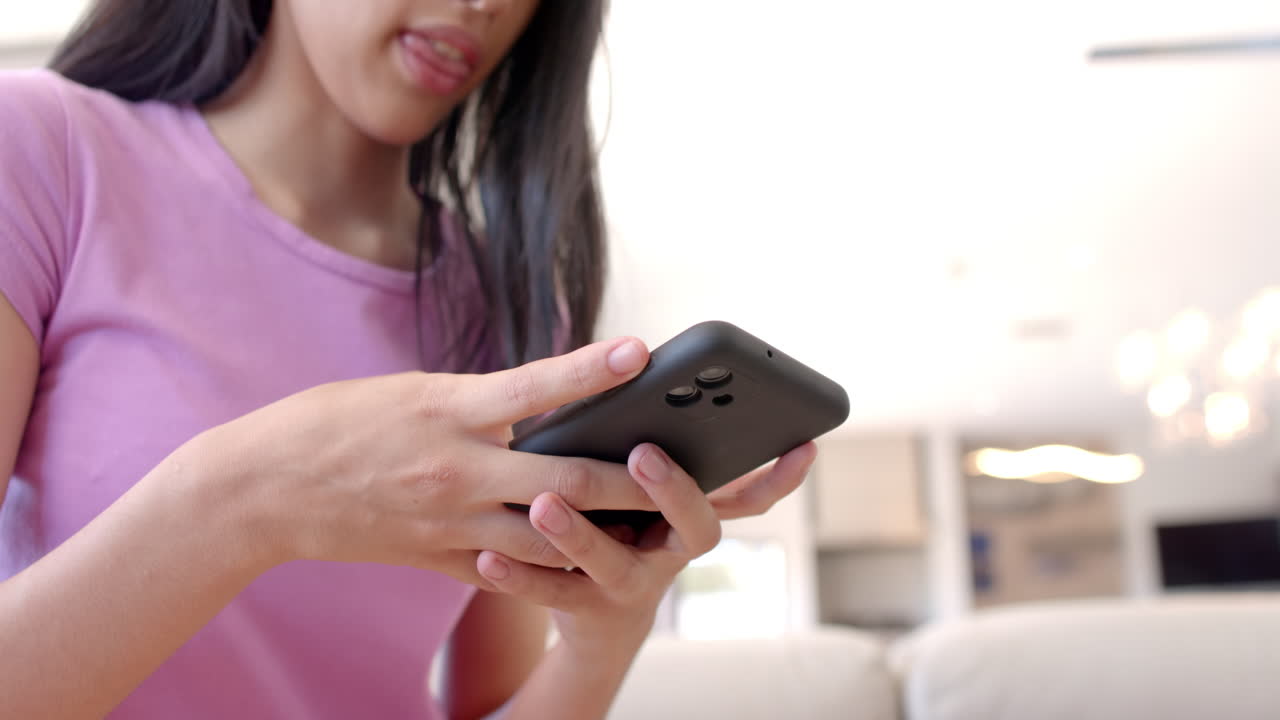 teenage girl holding smartphone, texting and browsing social media apps indoors