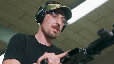 un hombre desarma el arma quitando el cargador y vaciando la cámara