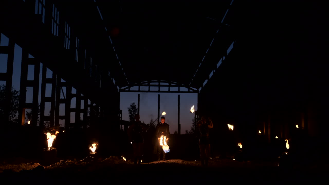 느린 동작: 가르에서 화재 쇼 세 명의 여성 예술가와 불꽃 던지기를 가진 남자를 보여줍니다.