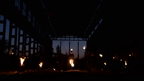 slow motion: fire show in the hangar show three female artist and a man with flamethrowers