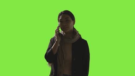 Low-Key-Studio-Shot-Of-Woman-Answering-Call-On-Mobile-Phone-Against-Green-Screen