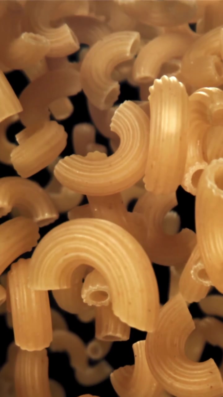 Pasta di maccheroni secchi che cade al rallentatore su sfondo nero