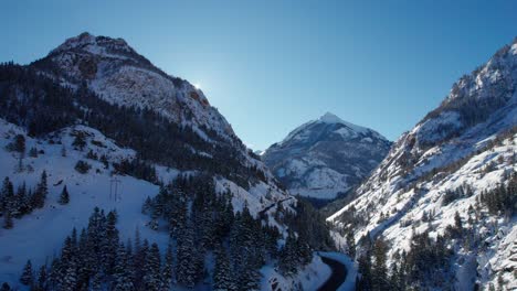 Panning-drone-shot-of-the-sun-coming-out-from-behind-a-mountain-on-a-sunny-day