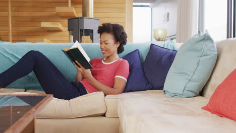 video de una mujer afroamericana leyendo un libro en el sofá