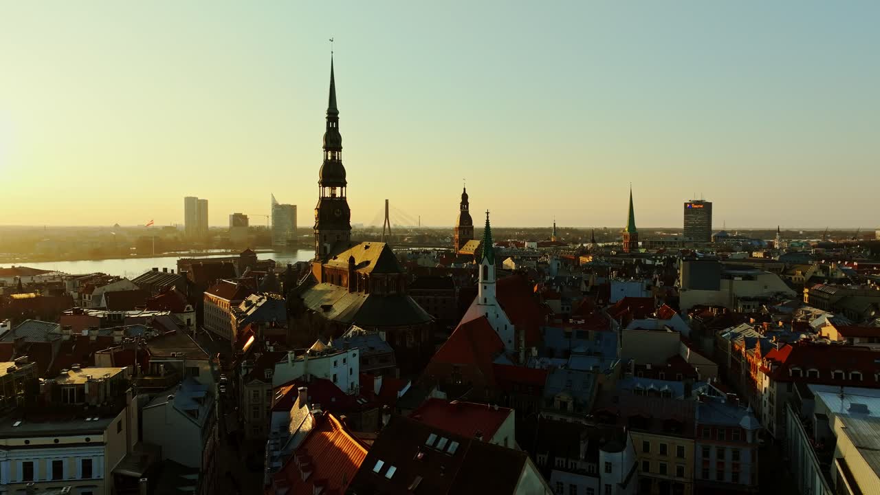 Cinematic drone flight over Riga historic skyline during warm golden sunset glow