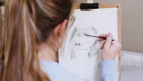 over the shoulder view of female teenage artist at easel drawing picture of dog in charcoal