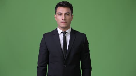 young handsome hispanic businessman against green background