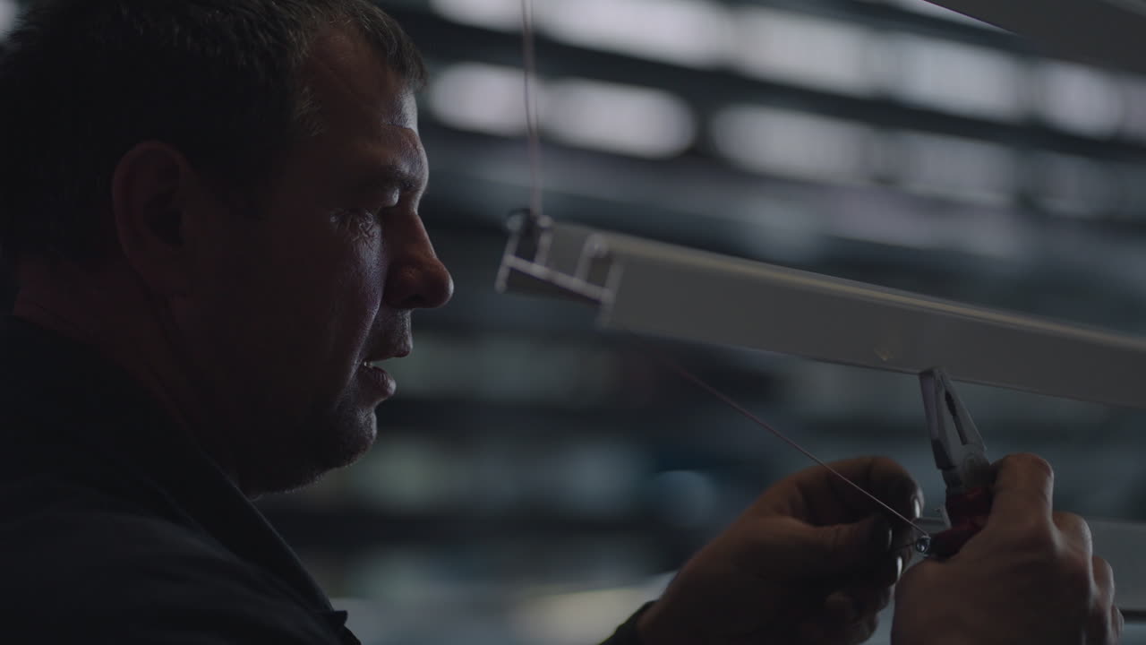 un anciano en la fábrica fija perfiles de acero para pintar. primer plano tímido en la fábrica en cámara lenta