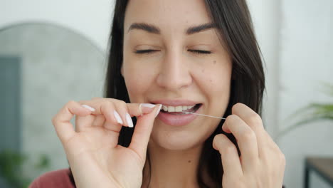 mujer lavándose los dientes con hilo dental