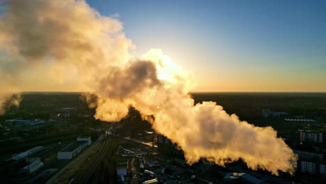 Drone-shot-of-the-sun-shining-through-a-pulp-mill's-steam