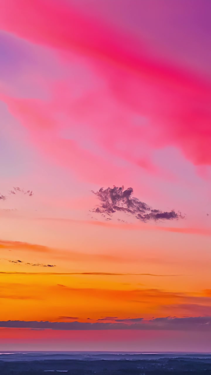 Cielo pastello al tramonto sopra l'orizzonte lontano con nuvole serali colorate, sfondo verticale aereo che emana un bagliore caldo e rilassante dal freddo al caldo