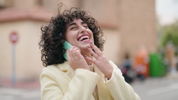 Giovane donna sorridente parlando fiducioso sullo smartphone in strada
