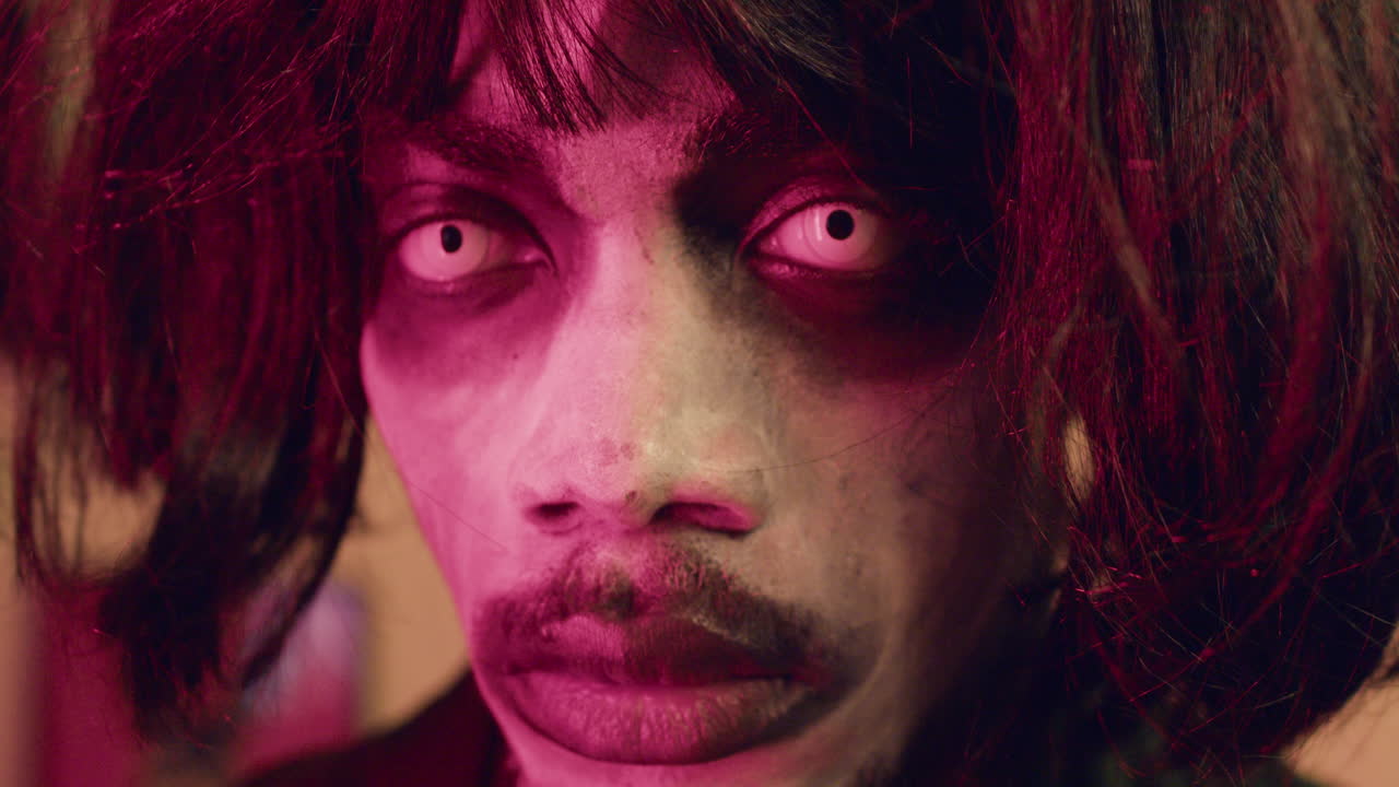 мужчина смотрит на камеру на вечеринке на хэллоуин.