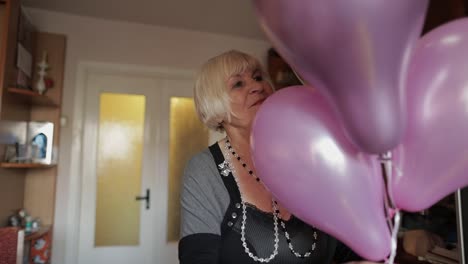 Cute-grandma-celebrates-her-birthday.-Holds-multicolored-balloons-in-her-hands