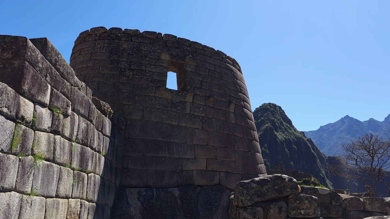 An exterior view of the magnificent Temple of the Sun at Machu Picchu, showcasing the unique curved stonework and precise Inca engineering of this sacred astronomical observatory