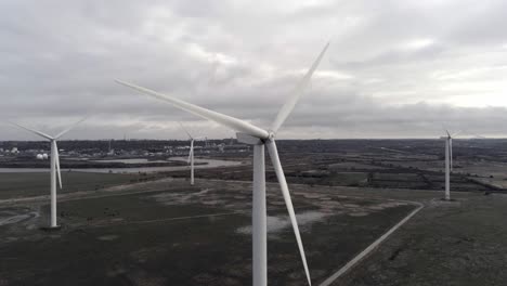 sustainable electrical wind turbines spinning on england farmland parallax orbit right aerial view