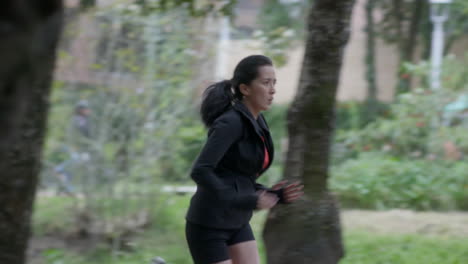 Una-Mujer-Vestida-De-Negro-Haciendo-Un-Sprint-Matutino-En-Un-Parque-De-La-Ciudad