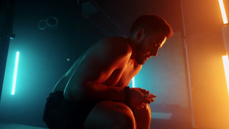 frustrated and tired sporty man is resting in gym hard training before competition