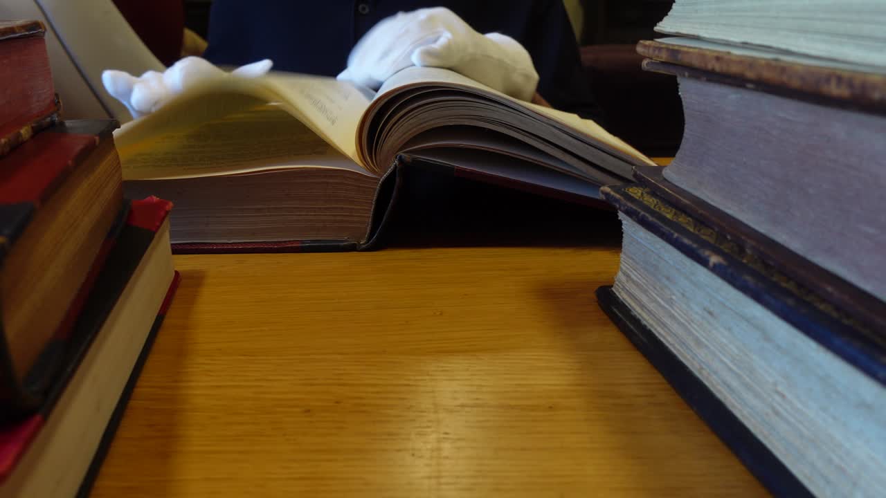 Man's hands leafing through an old book in the library